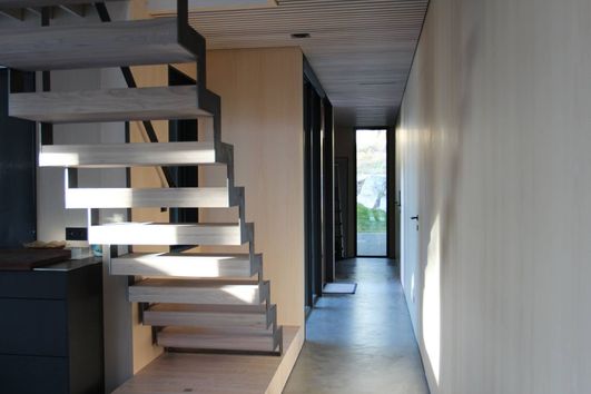 Moderne trapp som leder opp til andre etasje i en gang med mange vindu som slipper inn mye lys
