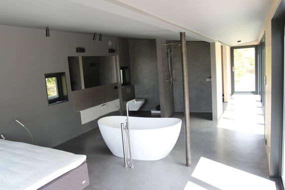 Moderne bad i et nybygg med et hvitt badekar, en dusj, toilett, speil og masse lys som slipper inn